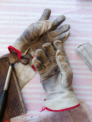Still life of leather work gloves with small hammer and pieces of worn sandpaper