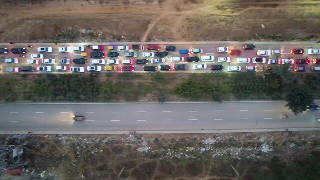 straight down drone night view of heavy traffic congestion on a Gurgaon road, showing urban commute, road infrastructure, and city transportation challenges with broken roads and waterlogging