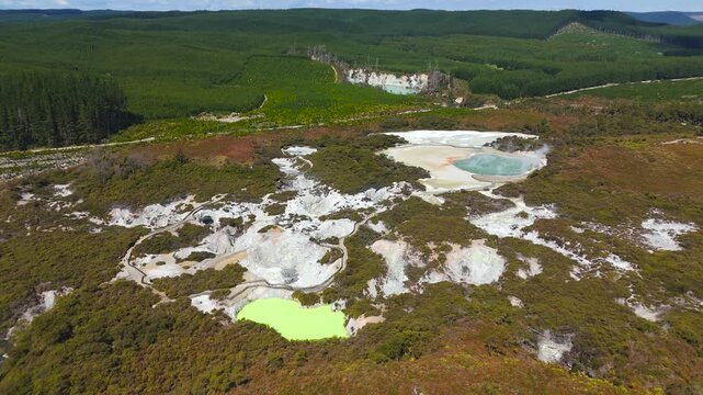 Champagne Pool and Devil&rsquo;s Bath glow in Waiotapu thermal wonderland near geothermal Rotorua, wide right orbit drone shot.