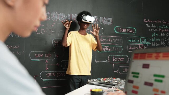 Closeup of school girl hand coding program while african student using VR interact with metaworld. Smart boy wearing virtual reality glasses and playing video games at innovative class. Edification