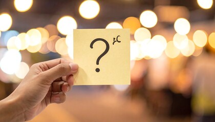 A hand holds a note with a question mark, bokeh background