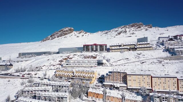Aerial 4K video from a drone to Sierra Nevada ski resort on a sunny winter day in the mountains, Spain. Sierra Nevada is the largest mountain range near the city of Granada in Spain with snow. Sierra 