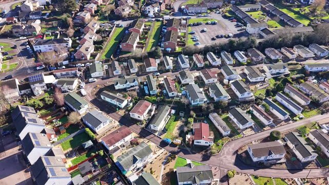 Drone aerial footage of Cinderford town in Gloucestershire, surrounded by the Forest of Dean, showing residential buildings, townscape, woodland, and rolling hills in a semi-urban rural landscape