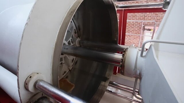Large heavy rotating orchard fruit press crushes apples into cider pulp
