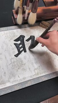 A close-up shot of a Chinese calligraphy master writing the character "Ju" (Gathering/Reunion) with a traditional brush, symbolizing family unity during the Spring Festival.