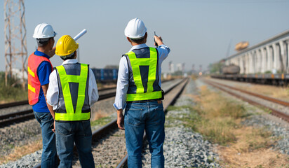 Multi-generational engineers discussing blueprints on a construction site, asian construction workers and an architect smiling at a building project, professional engineers in hard hat and safety vest