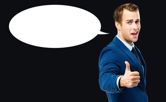 Photo of excited businessman showing thumbs up like hand sign gesture, in blue confident suit, standing over black background. Handsome happy man at studio. Copy space for some slogan or text.