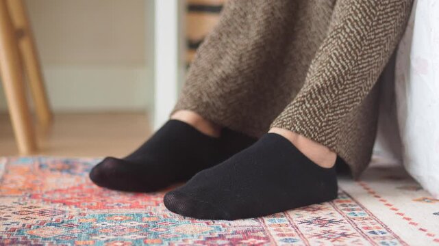 Person sits on rug with black socks on their feet