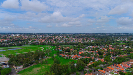 Obraz premium Panoramic Aerial Drone view of Inner Western Suburbs of Sydney housing, roof tops, the streets and the parks, the roads and trees of Ashbury Ashfield Burwood Summer Hill Canterbury and Campsie in Sydn