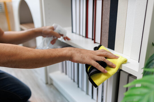 A man is cleaning his house on holiday. He dusts shelves, wipes down small decorative plants, and polishes home decorations with enjoyment.
