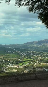 Carretera del Puig, 03739 Javea, Alicante, Spain. October 20, 2025. Vertical video shot from a car. Beautiful view from above of the city in green colors. landscape with clouds