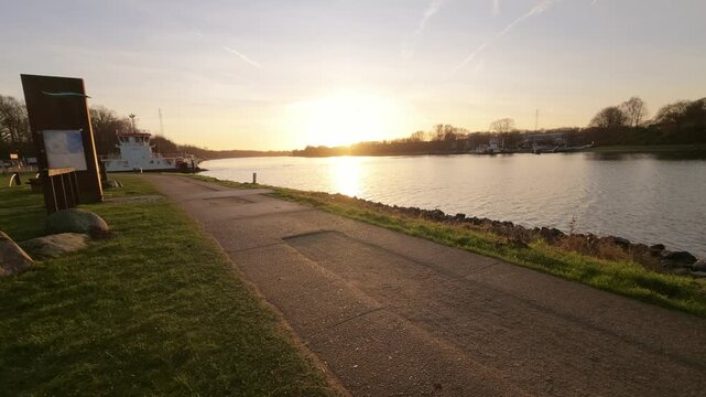 Slow camera movement along the Nordostseekanal in Rendsburg Germany at sunset with calm water and a ferry visible in warm evening light