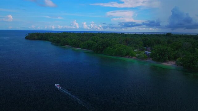 Fishing boat Yuo Island village Wewak Sepik Region aerial drone Papua New Guinea PNG Papua Niugini sunny blue sky untouched coastline beach coral reef Madang Bismarck Sea Pacific Ocean circle left