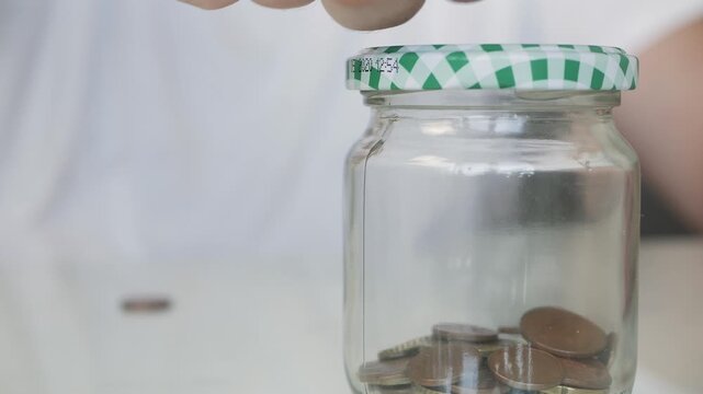 Elderly Person Putting in a Piggy Bank Jar Coins. Savings Made in the Piggy Bank by Putting Various Coins.