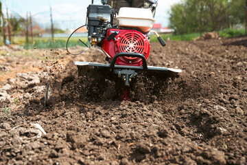 Farmer using tiller on a plowed field © erika8213