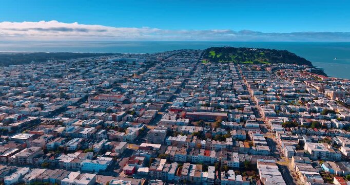 Densely built urban landscape of modern San Francisco, California, USA. Sunlit residential neighborhoods from drone footage. Ocean waterscape at backdrop.