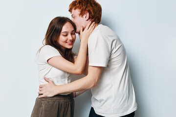 Fototapeta premium Couple, love, embrace, and affection with man kissing woman on cheek in studio. Happy relationship, casual clothing, and smiling young people for romance and intimacy.