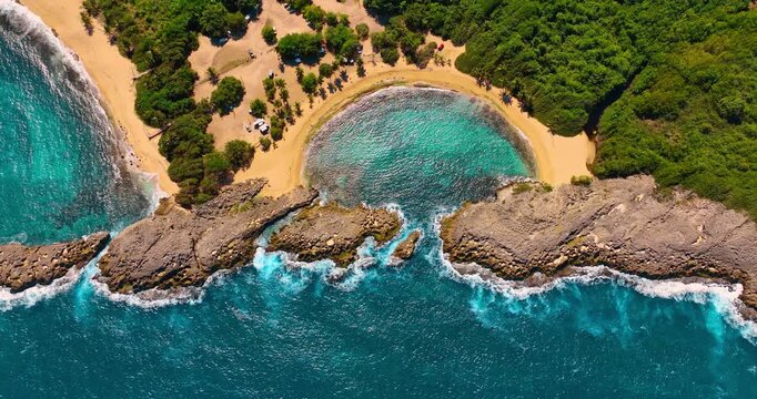 Aerial drone shot of Mar Chiquita beach rocky coastline. High angle view of a natural horseshoe bay surrounded by jagged rocks and tropical greenery.