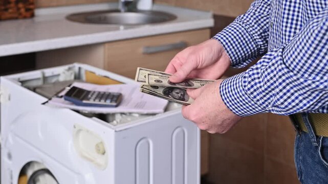 A man counts $100 bills for repairing a broken washing machine. Concept for paying for repairs and services.