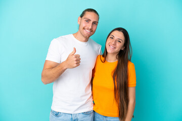 Obraz premium Young caucasian couple isolated on blue background giving a thumbs up gesture