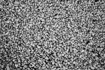 Monochrome macro close-up of a detailed textured surface composed of numerous small, irregularly shaped pebbles or crushed stone aggregate, creating a visually rich and abstract background, 