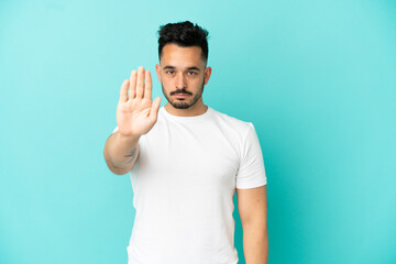 Fototapeta premium Young caucasian man isolated on blue background making stop gesture