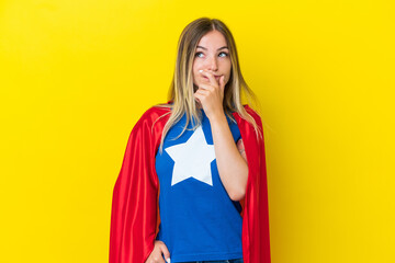Super Hero Romanian woman isolated on yellow background having doubts and with confuse face...
