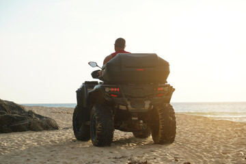 Fototapeta premium A man engages in extreme ATV riding on sand beach early in the morning