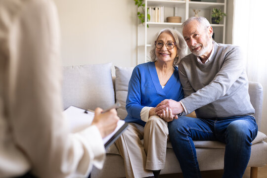 Senior couple holding hands talking with therapist.