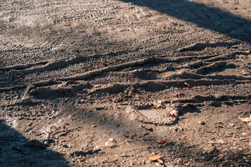 Gritty Construction Site With Deep Tire Impressions Through Sunlit Mud And Gravel