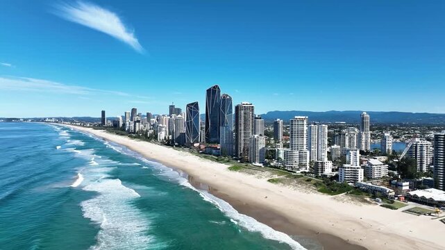 Drone view of Main Beach looking south toward Broadbeach and Burleigh &mdash; golden sand, turquoise waves crashing, sunlit surf, reflecting off the Jewel Building along the vibrant Gold Coast shoreline.