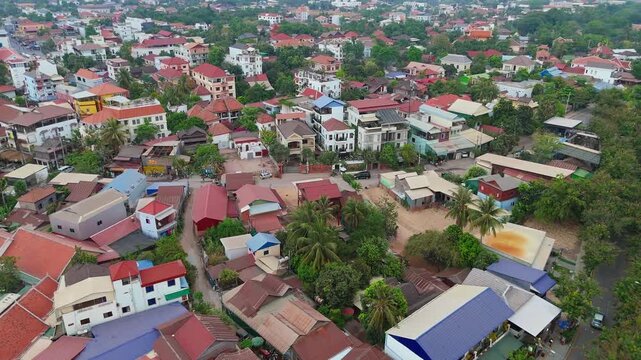 An aerial drone shot of Kampong Cham, Cambodia, showcasing vibrant red-roofed houses, lush greenery, and local infrastructure in a bustling urban area, offering a glimpse of the region&rsquo;s daily life.