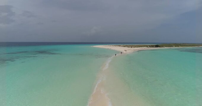 Stunning aerial view of the famous sand isthmus at Cayo de Agua, Los Roques Archipelago, showing tourists walking on pristine white sand surrounded by turquoise Caribbean waters.