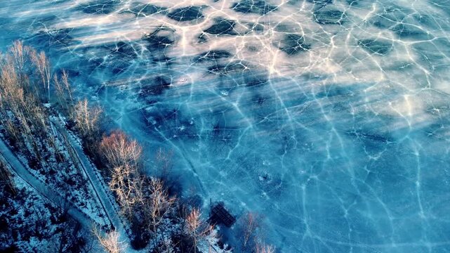 Stunning straight-down aerial view of fractured ice patterns on Matanuska Lake. Deep blue and white foggy ice creates mesmerizing geometric cracks and fractures following a brief warming spell.