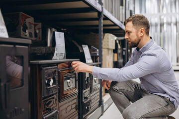 Fototapeta premium Man examining a wood stove, browsing home heating equipment in a large retail store, making a purchase decision