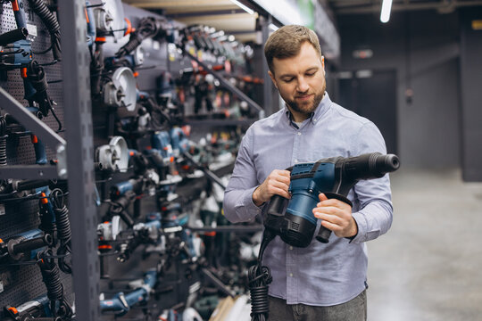 Man shopping for power tools in a hardware store, selecting a hammer drill for construction and home improvement