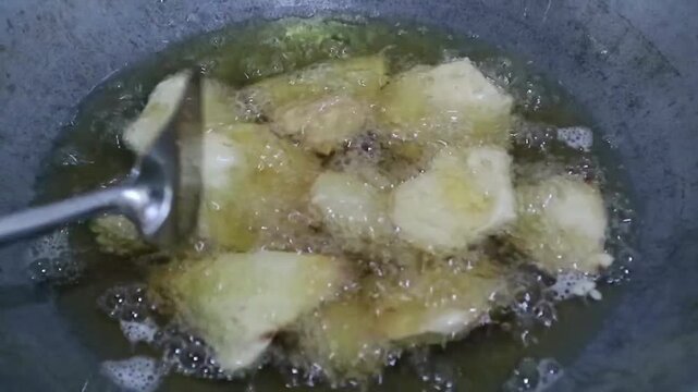 Deep frying sliced sweet potato in hot oil inside a wok. Popular Indonesian snack known as Ubi goreng