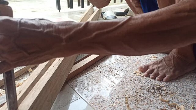 The hands of a carpenter opening wooden planks that are stuck together with a hammer, a pry bar and a chisel on the terrace of the warehouse
