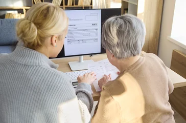 Fotobehang Onderzeeër Daughter guides senior grandmother through online bills payment. They review an invoice on the computer, confirm utilities and taxes, and update accounts. Family finance support and care.  © Studio Romantic