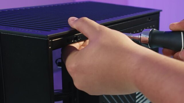 Unscrewing a screw with a screwdriver to detach the side panel of a desktop computer case before maintenance or upgrade
