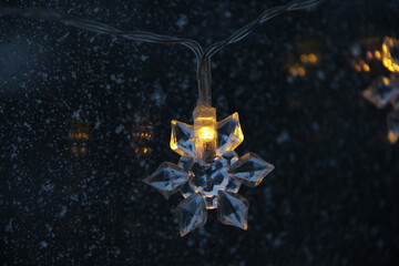 decorative snowflake light string on frosty window