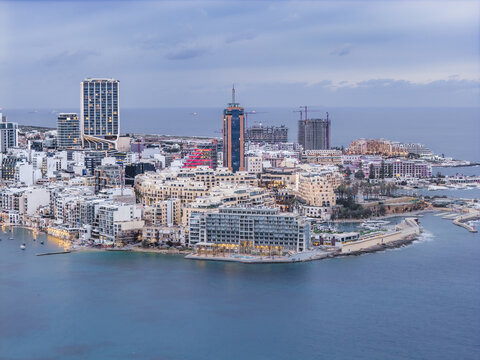 Aerial view of the vibrant cityscape where modern towers meet the azure sea, cradling the heart of St. Julian's, Sliema, Malta.