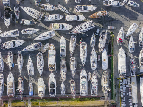 Aerial view of myriad boats, yachts, and vessels, a mosaic of white hulls against the dark harbor, reflecting the bright sun, Sliema, Valletta, Malta.