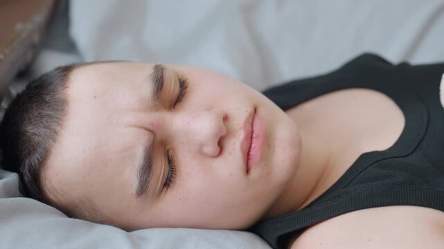 Close up of mother hand with polished nails gently touching nose of son resting with closed eyes as he wakes up smiling showing warmth tenderness care