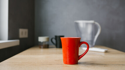 Red coffee mug on wooden table in minimalist kitchen setting