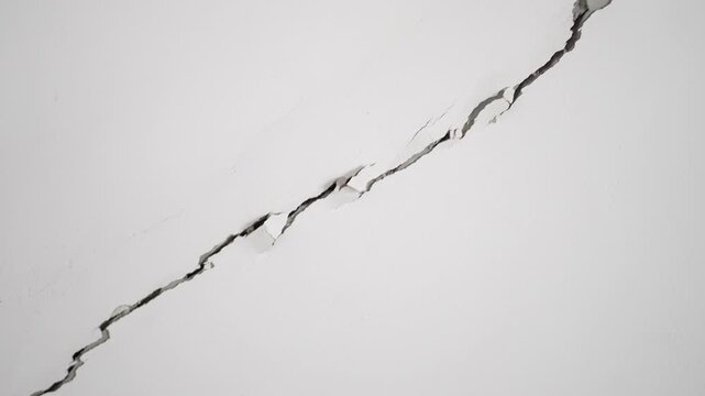 Large Diagonal Crack in White Concrete Wall or Ceiling Showing Structural Damage