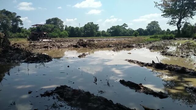 Tractor Plowing Muddy Paddy Field in Rural Sri Lanka, Traditional Rice Farming Agriculture