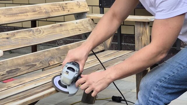 A man sends a homemade wooden bench using a grinder tool.
