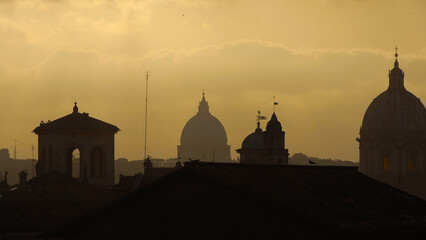 Rome historical center old skyline with iconic St Peter dome silhouette with afternoon yellow sky