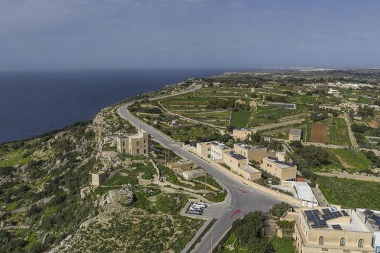 Aerial view of the winding road stretching along the rugged coastline, where the deep blue sea meets the dramatic cliffs, Dingli, Malta.